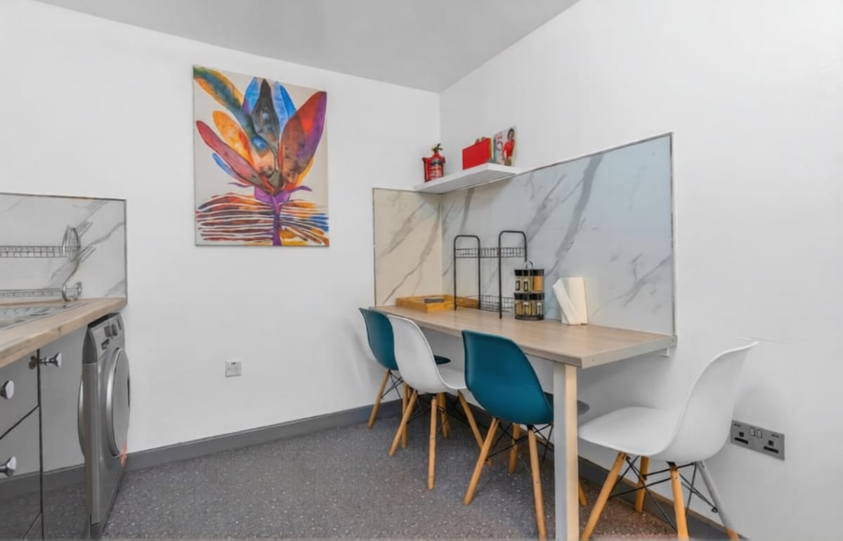 Breakfast bar with teal and white chairs against a marble-effect splashback, with a washing machine alongside.