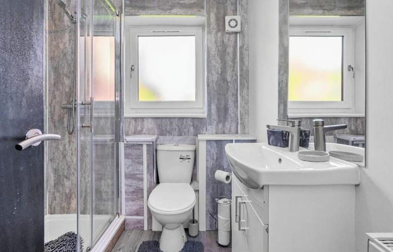 Shower room with a glass enclosure, a wall-hung basin, and two frosted windows.