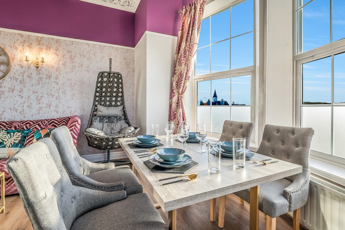 Dining table for six in a bay window looking over the river, with a hanging chair alongside.
