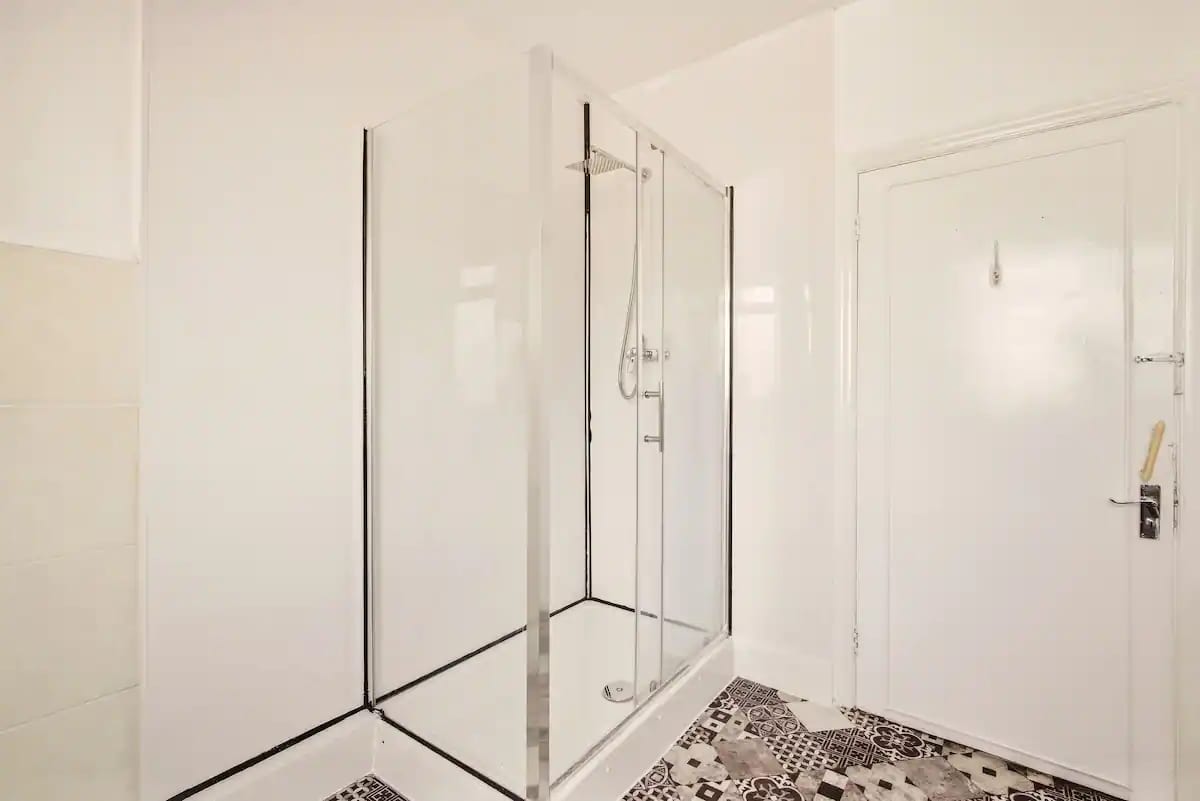 Shower room with a large walk-in shower behind glass screens and patterned floor tiles.